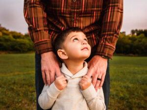 grand rapids michigan family photographer shoot in field with son looking up at dad
