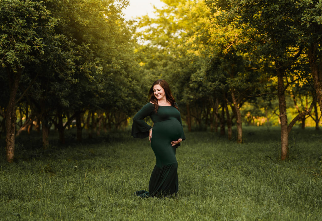 Maternity Photographer, Woman in long green dress standing on a grassy area