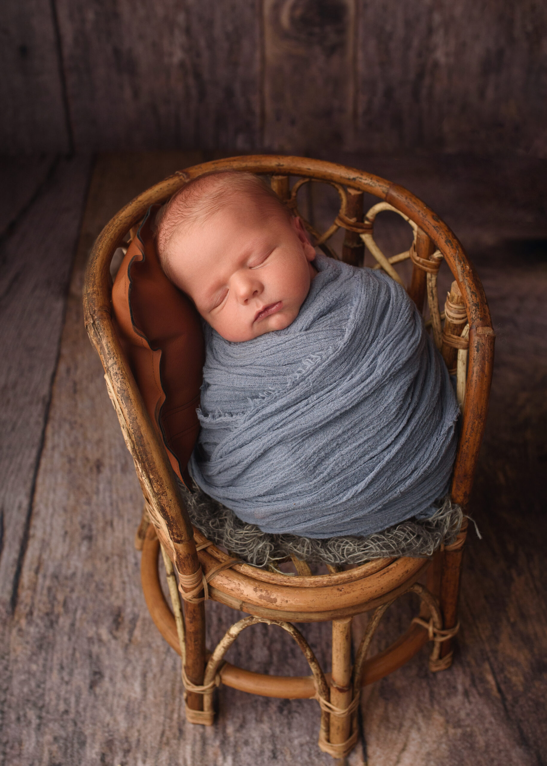 grand rapids newborn photographer baby boy in swaddle in a chair