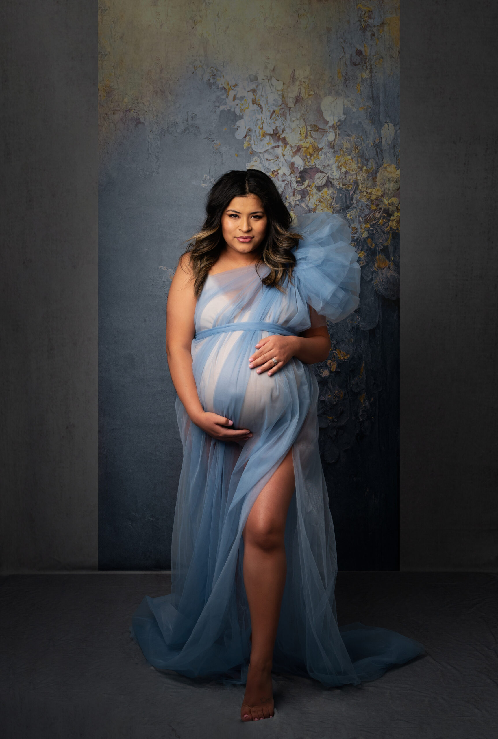 grand rapids maternity photography pregnant woman holding belly wearing blue dress