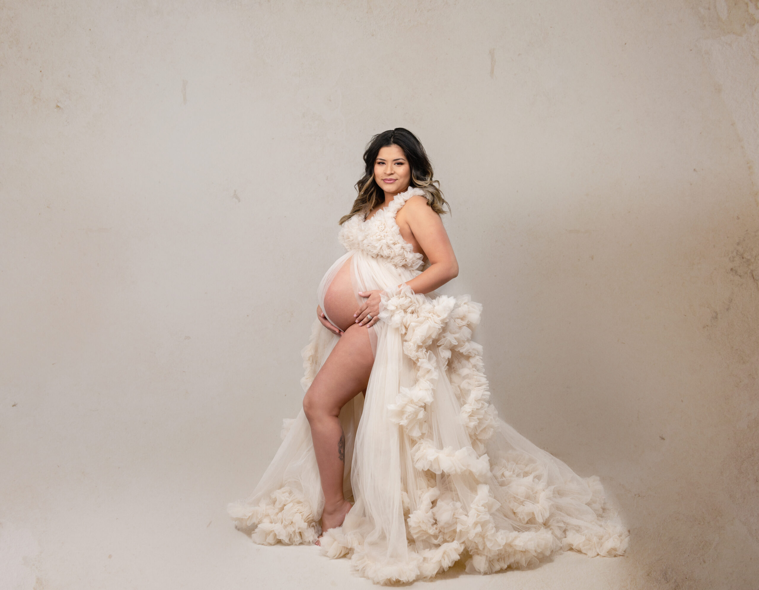 grand rapids maternity photographer pregnant woman with cream color dress looking at camera