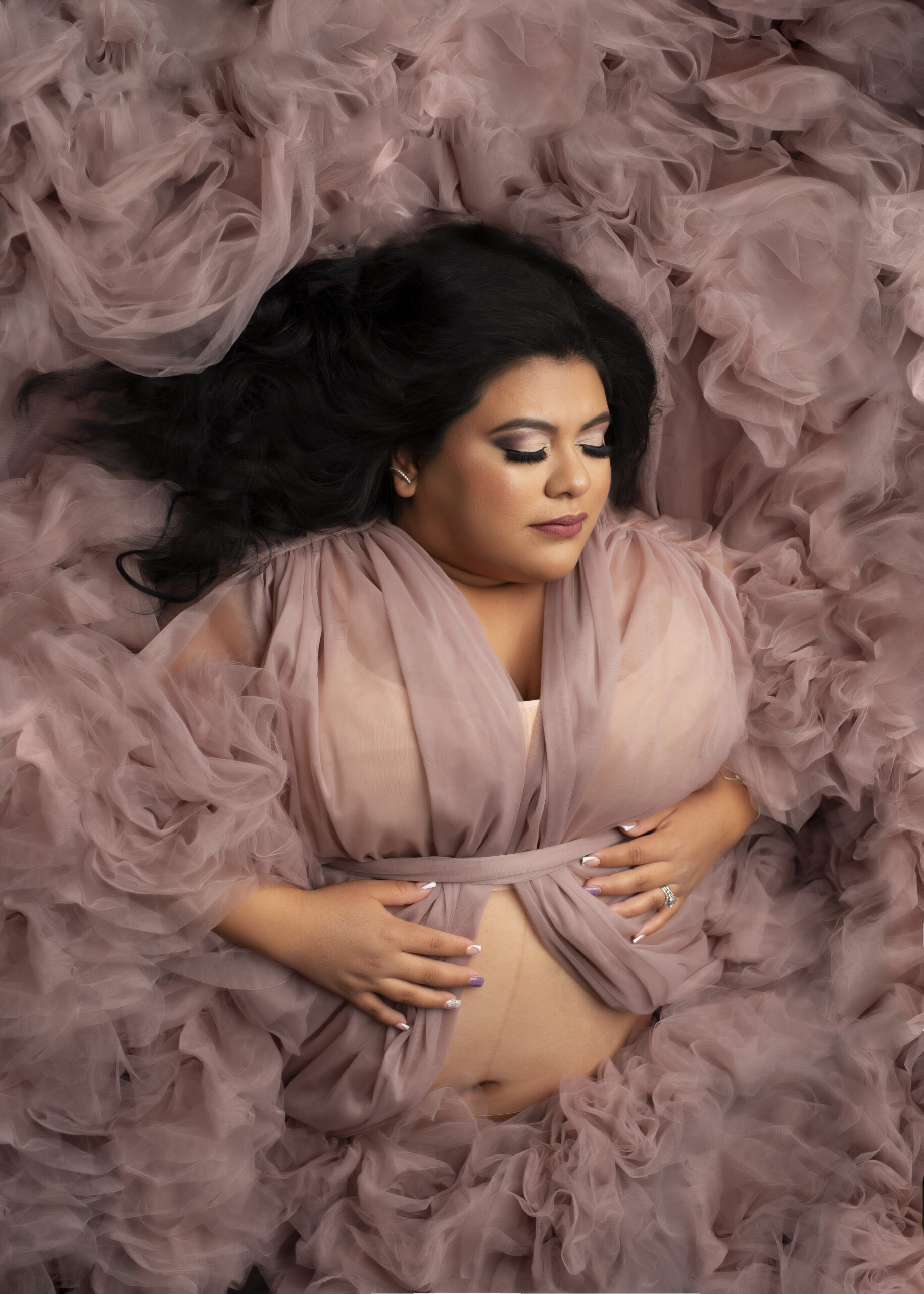 Grand rapids maternity photo session mother laying down holding baby bump in pink dress