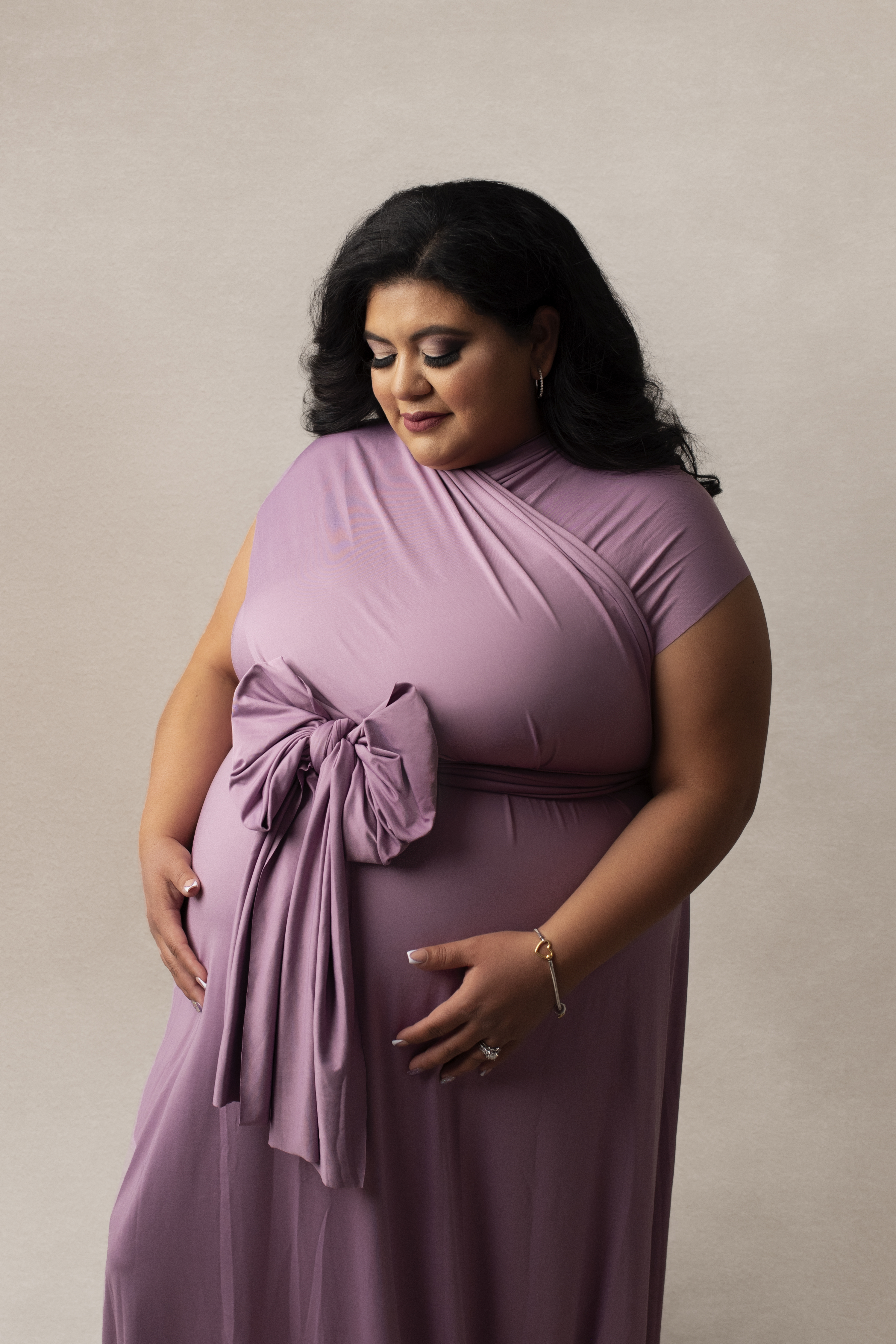 Grand rapids maternity photo session mother in purple gown looking at baby bump