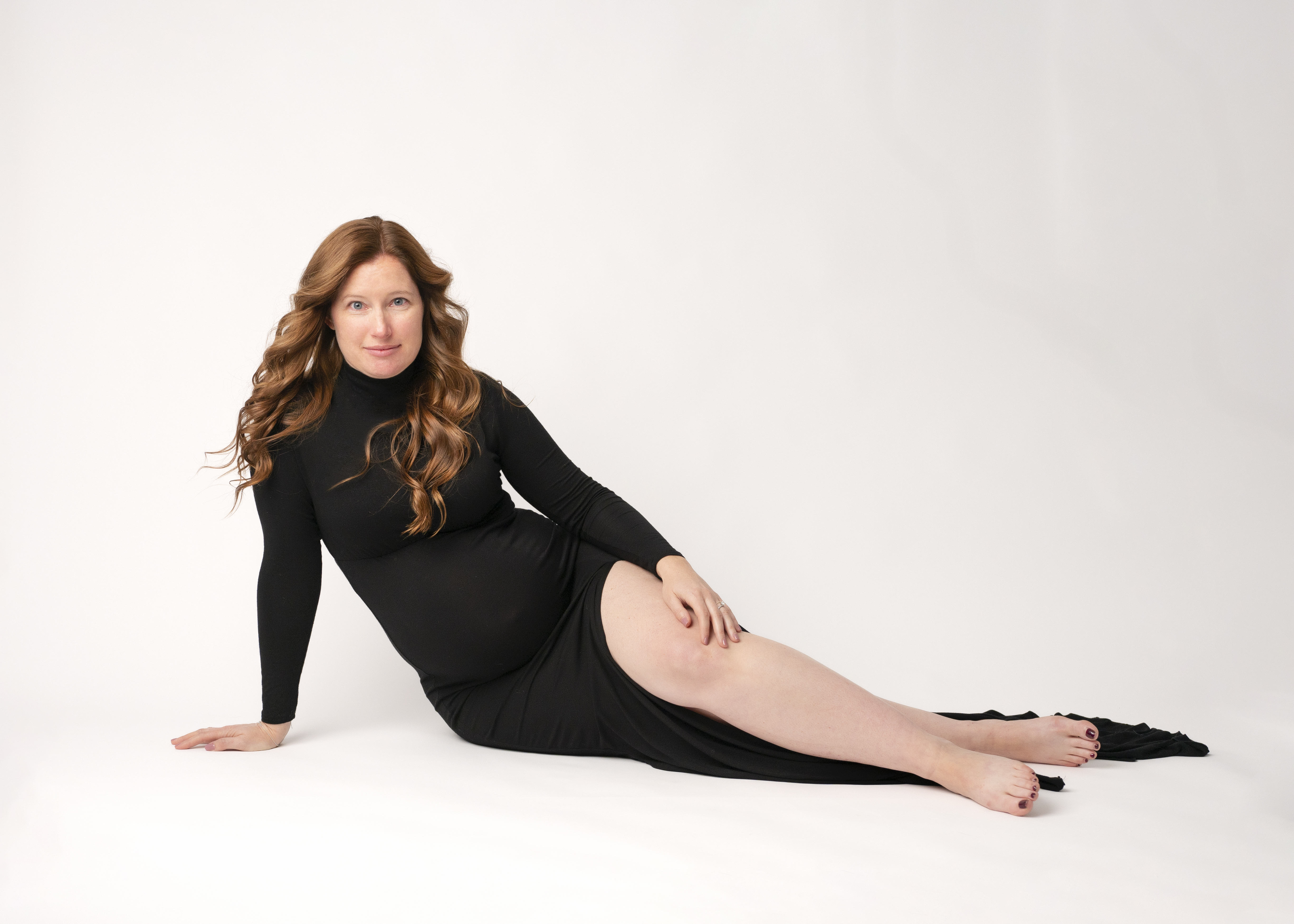 grand rapids maternity photo shoot mother in black dress sitting on her side
