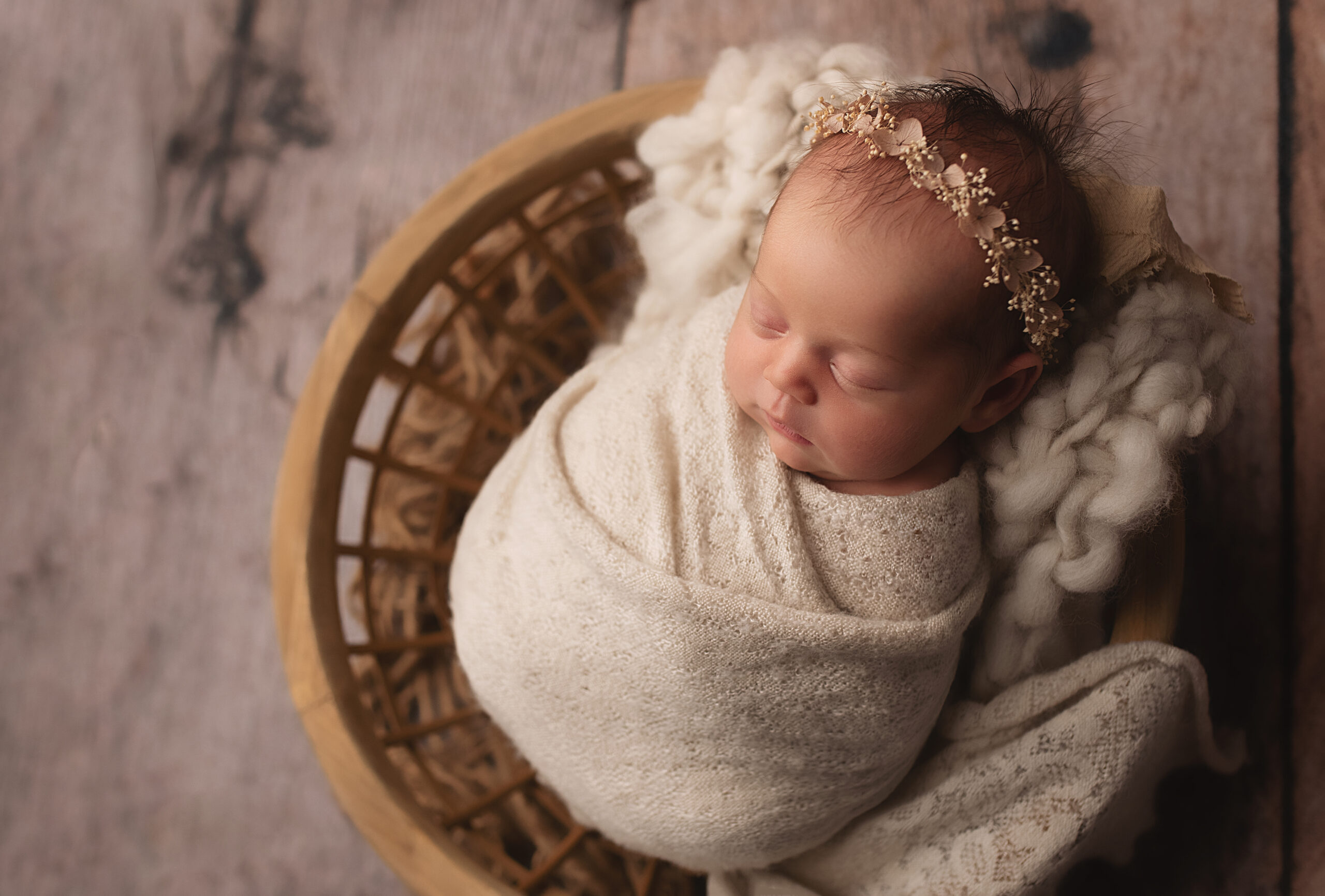 Grand rapids newborn photo shoot baby wrapped in cream swaddle in a basket