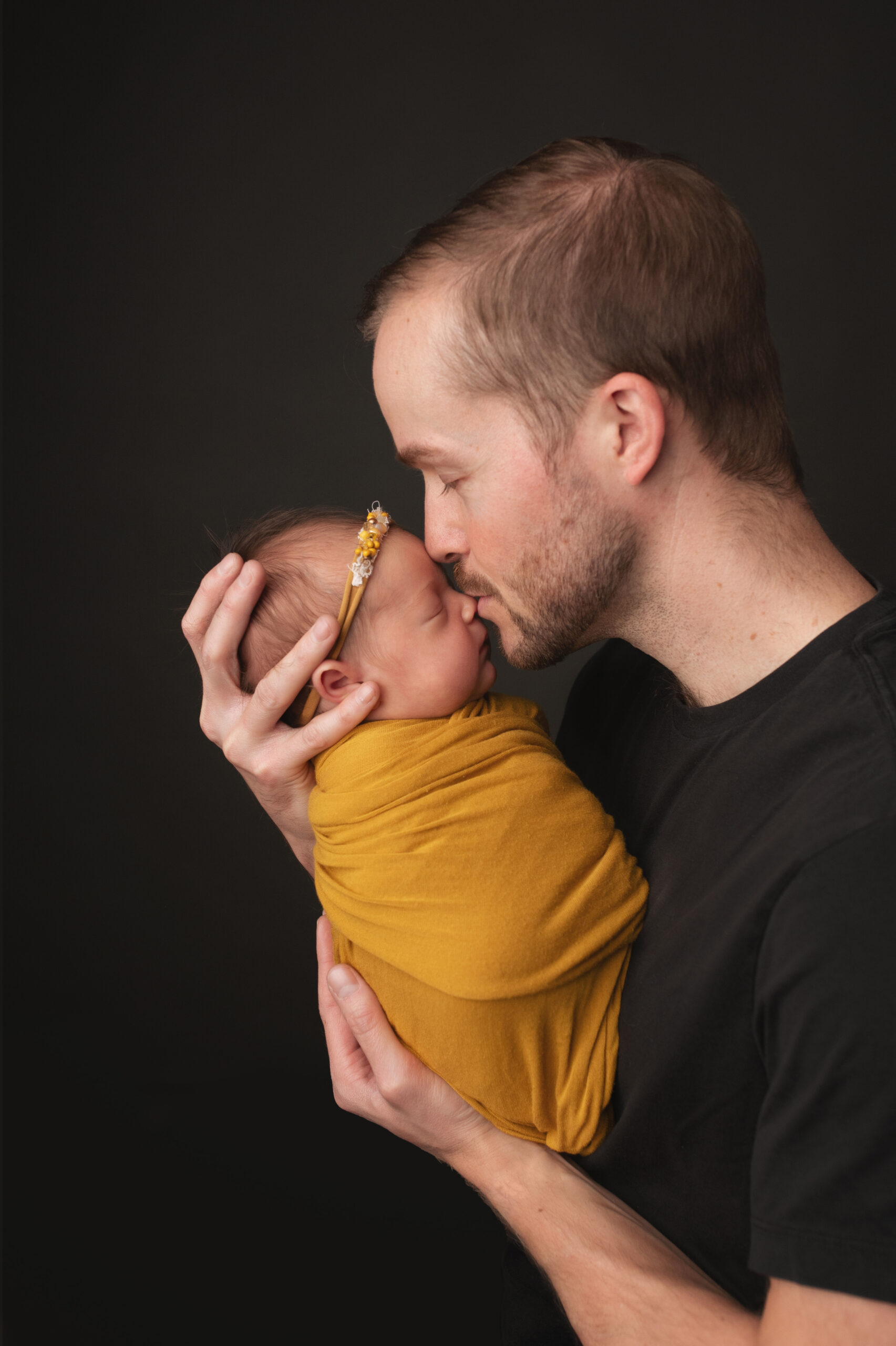 Grand rapids newborn photo session dad holding baby close and giving her a kiss