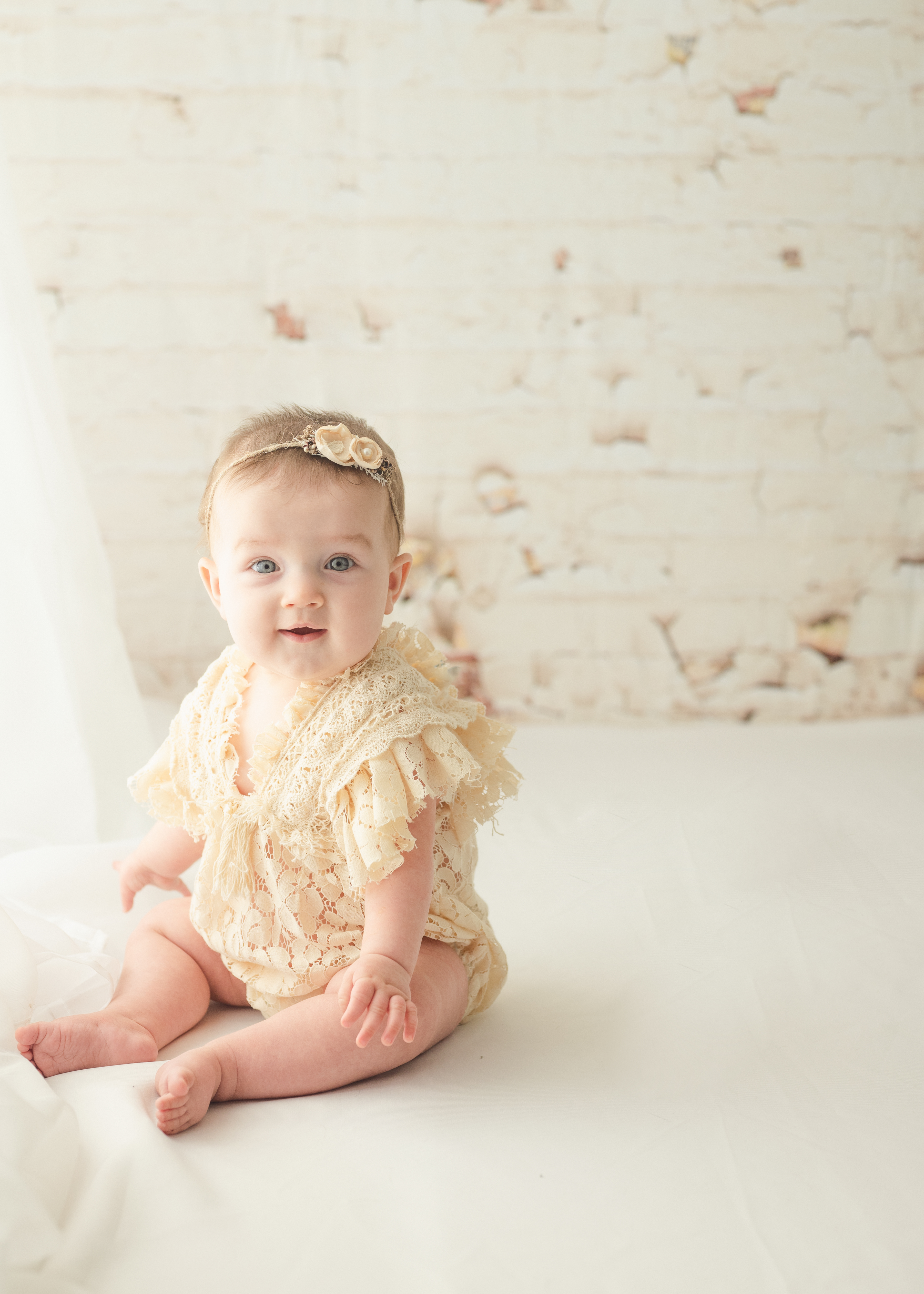 grand rapids baby photo session sitter baby girl in cream boho outfit smiling