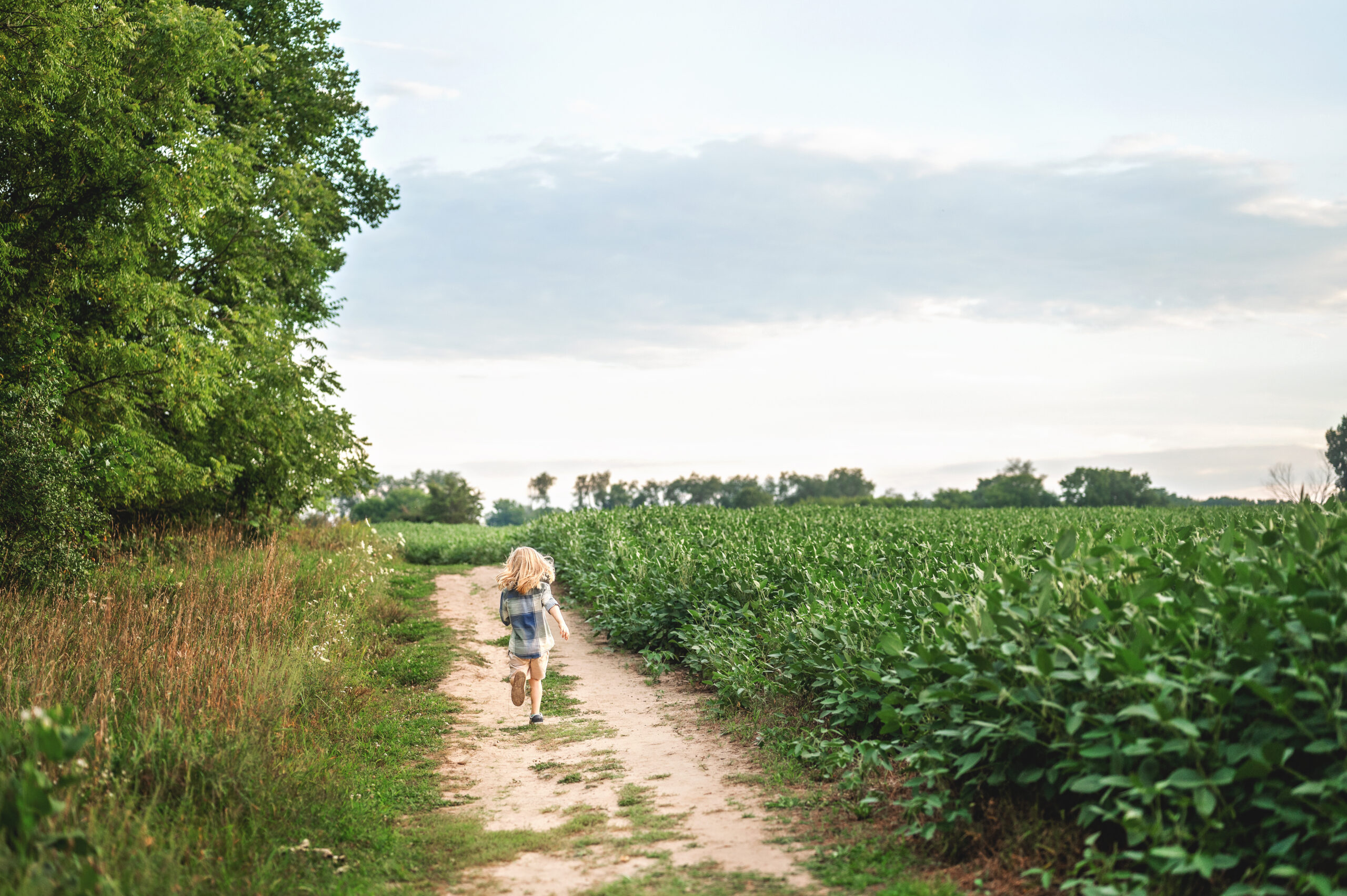 kid running on a dirt road with a blue sky