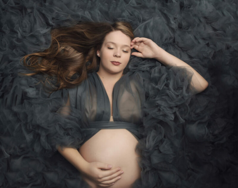 Maternity Photography, woman laying down in a dark green flowing dress
