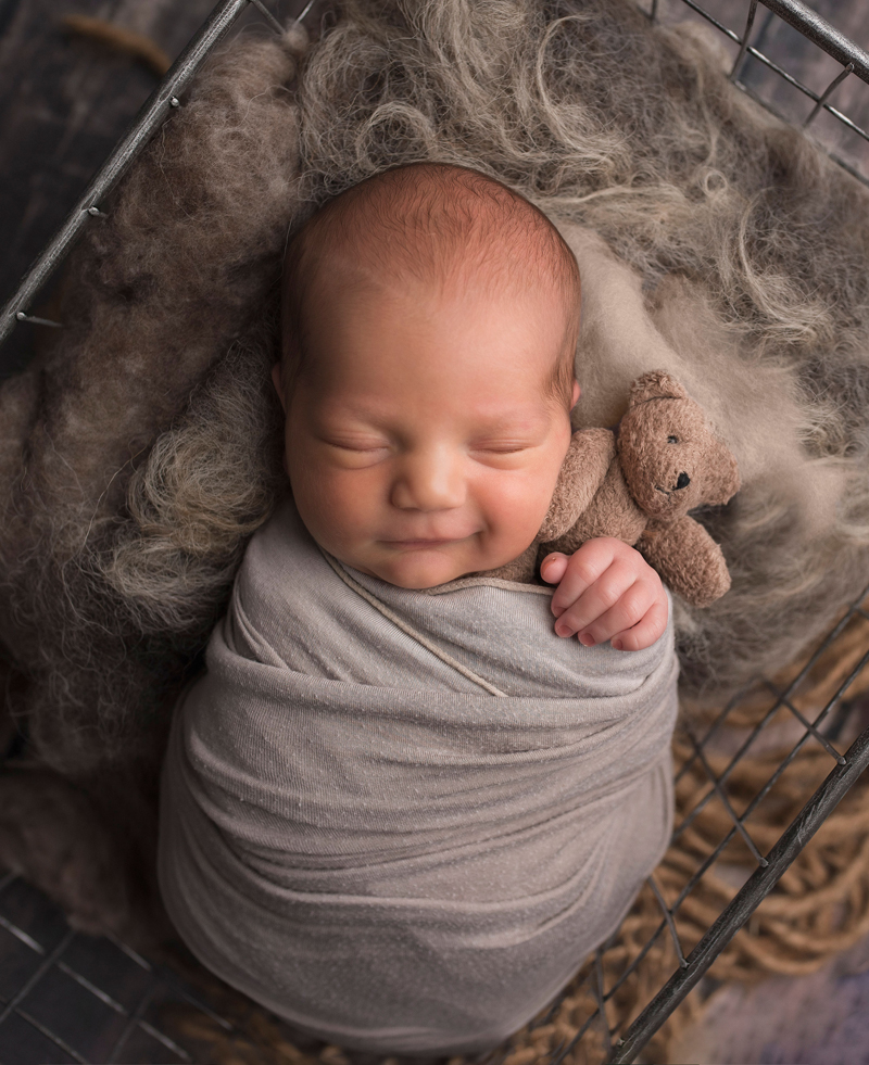 Newborn Photography, baby swaddled in grey blanket, laying in basket with brown bedding