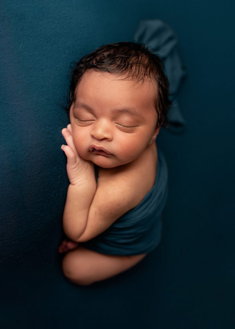 Newborn Photography, Baby swaddle in blue blanket on a blue background